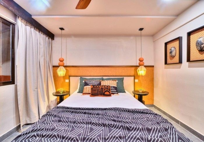 Bedroom with bed, bedside tables, pendant lights, and wall art; neutral colors.