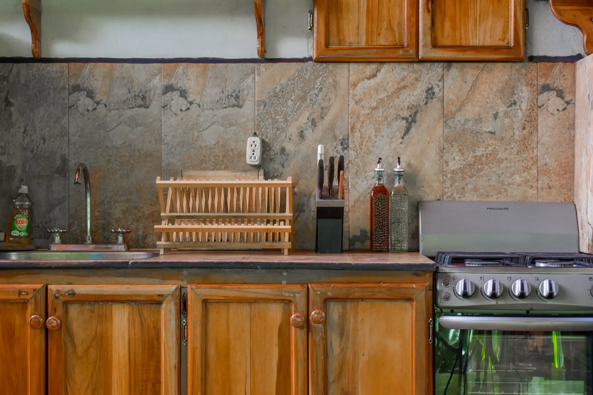 Kitchen with wooden cabinets, stone backsplash, and stainless steel appliances.