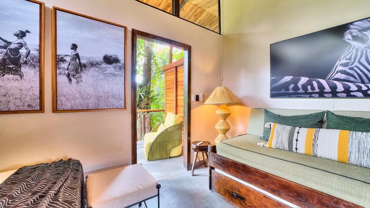 Interior room with open door to a balcony; couch, artwork, and lamp.