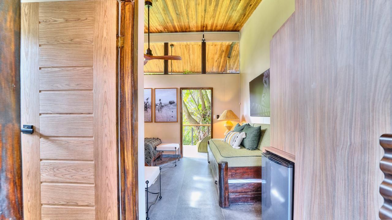 Interior view of a room with open door, showing a sofa, art, and natural wood accents.