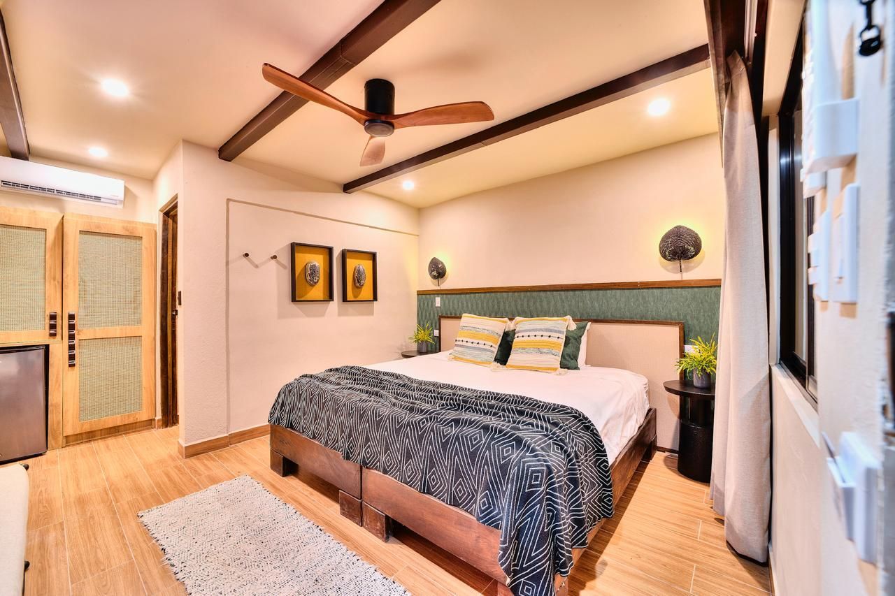 Bedroom with bed, rug, wooden doors and ceiling beams.