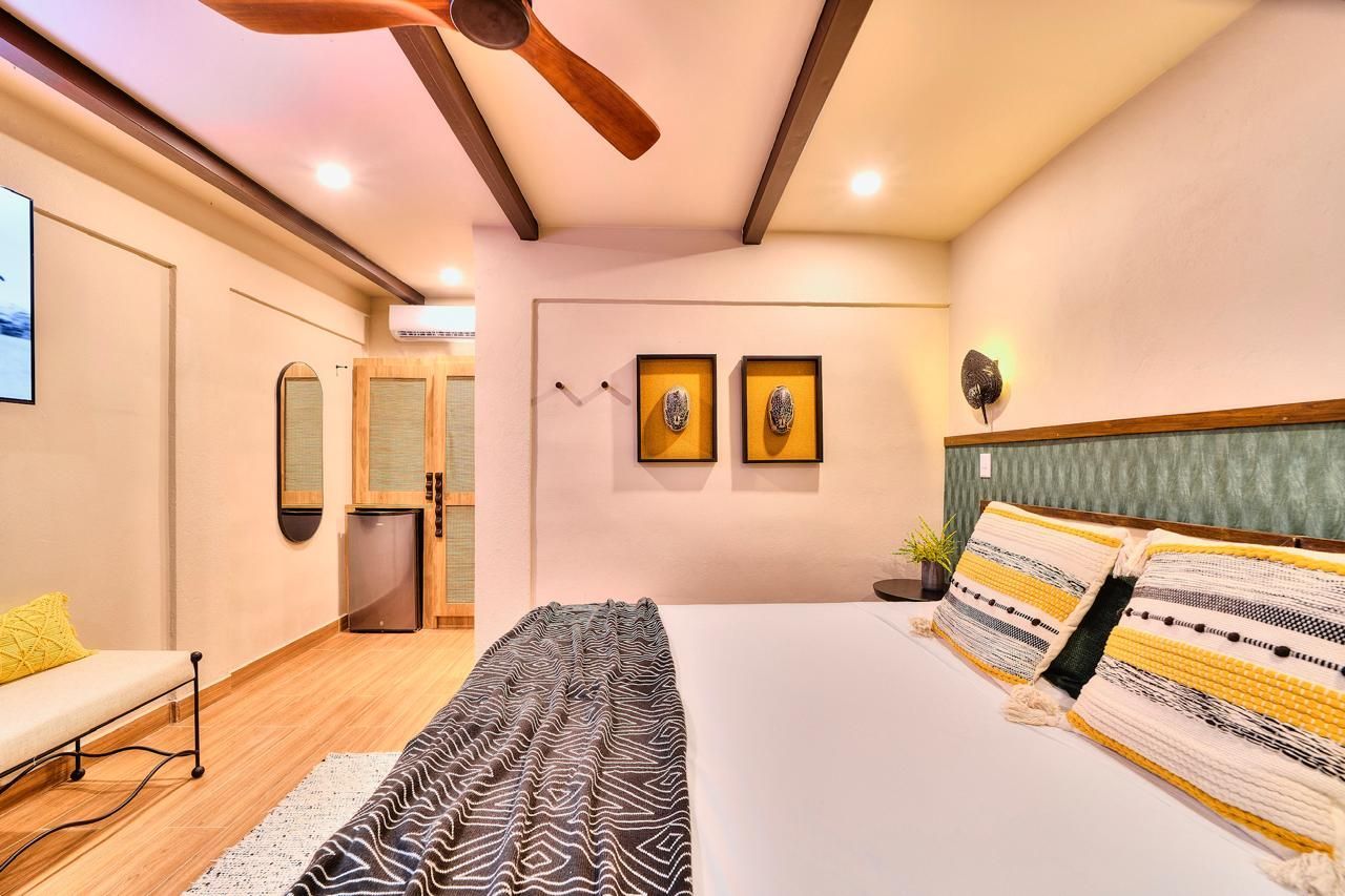 Bedroom interior with a bed, bench, artwork, and exposed beams.