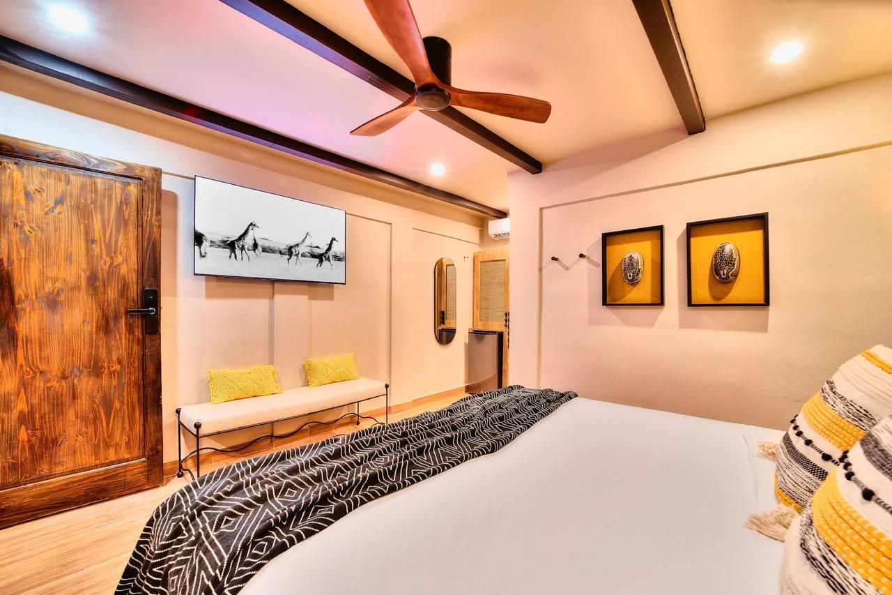 Bedroom with a large wooden door, ceiling fan, and bed with decorative pillows and blanket.