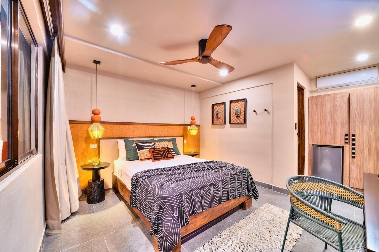 Bedroom with a bed, nightstand, ceiling fan, chair, wardrobe, and mini-fridge.