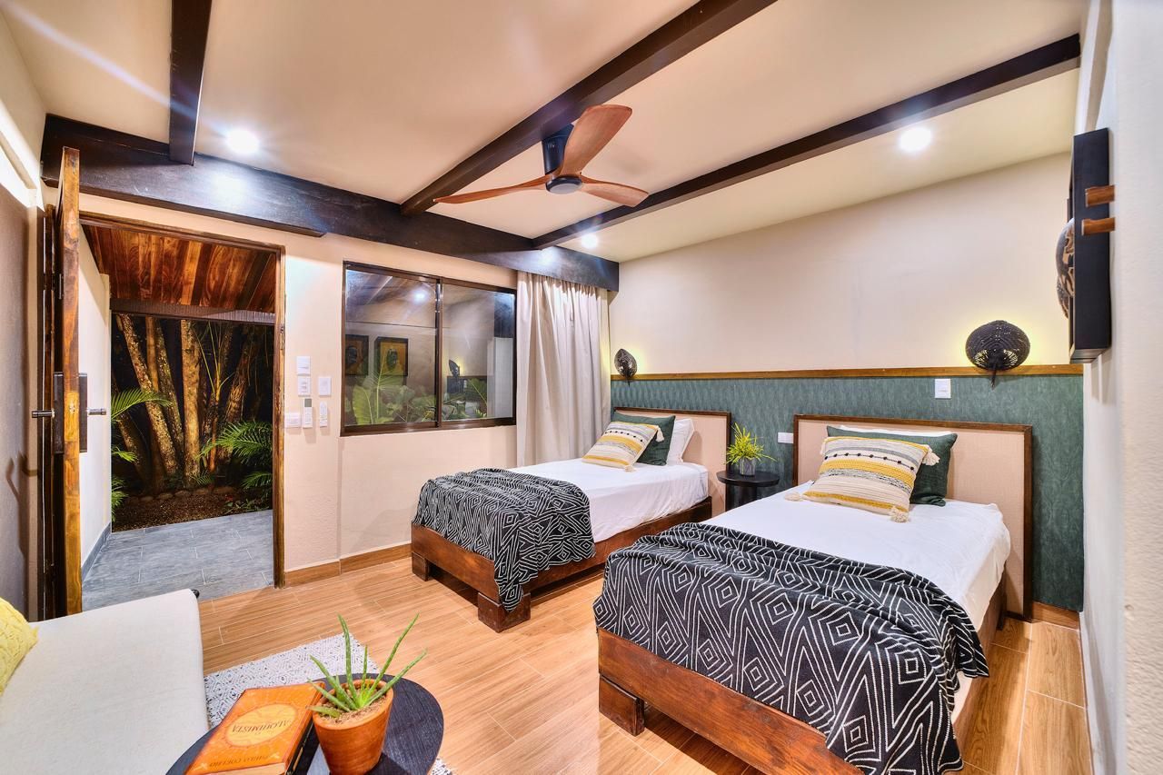 Bedroom with two twin beds, dark wood accents, and an open doorway to a garden.