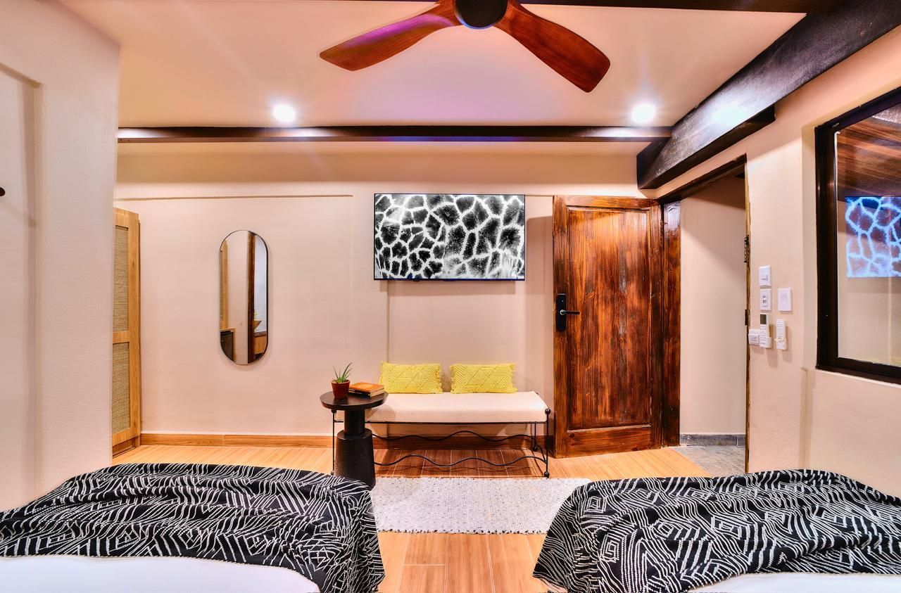 Bedroom with two zebra print beds, a bench, a wooden door, and a ceiling fan.