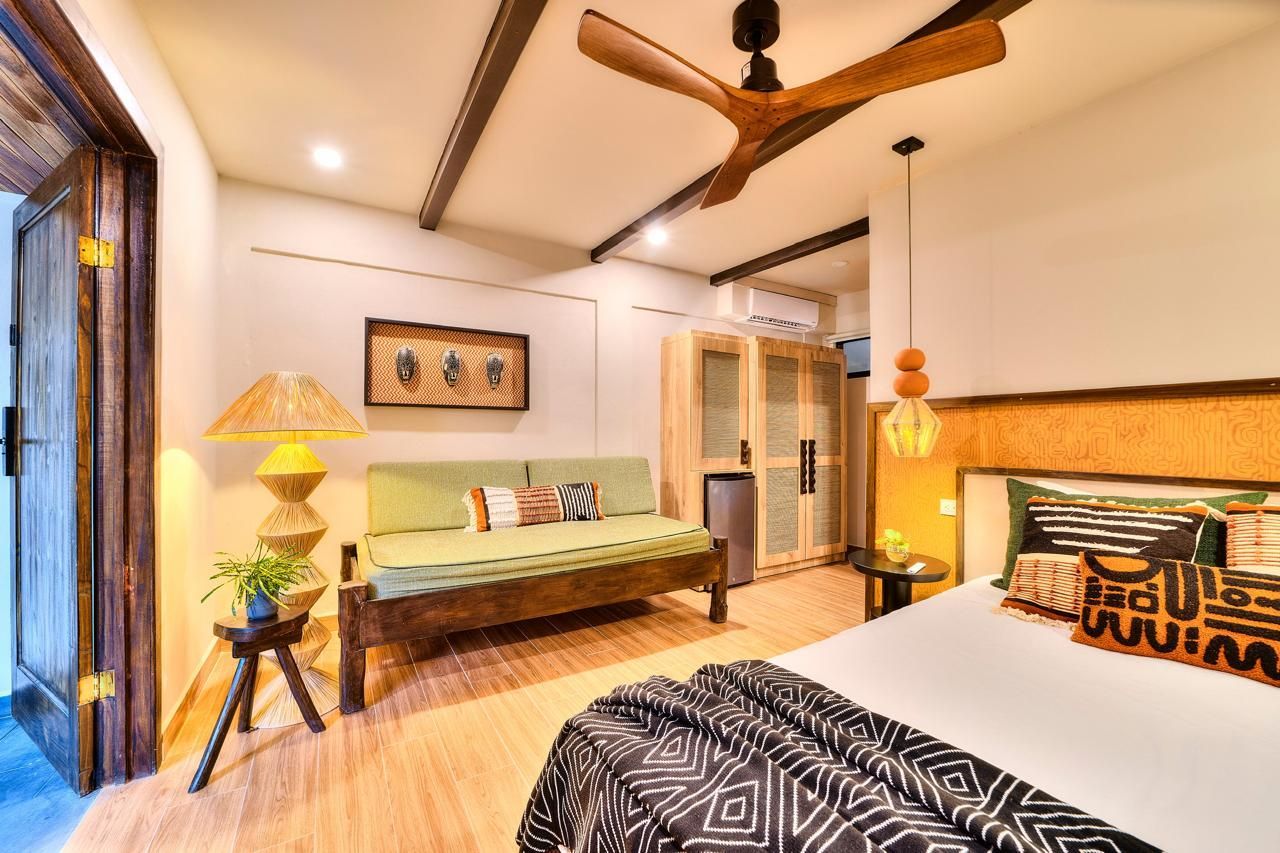 Bedroom with wood furniture, green sofa, ceiling fan, and bed with patterned pillows.