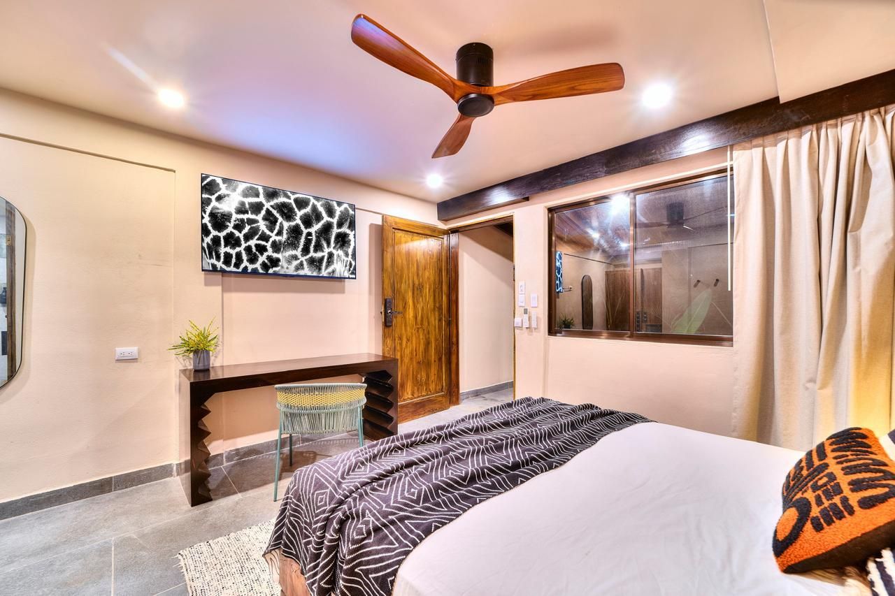 Bedroom with bed, giraffe art, dark wood accents, and a ceiling fan.