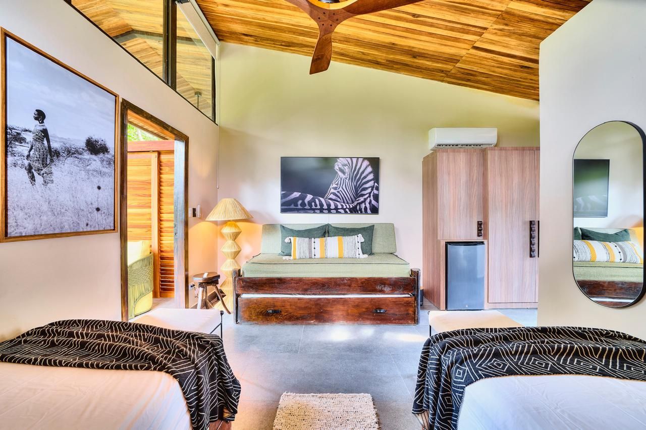 Bedroom with two twin beds and a double bed, decorated with animal-themed art and light wood furniture.