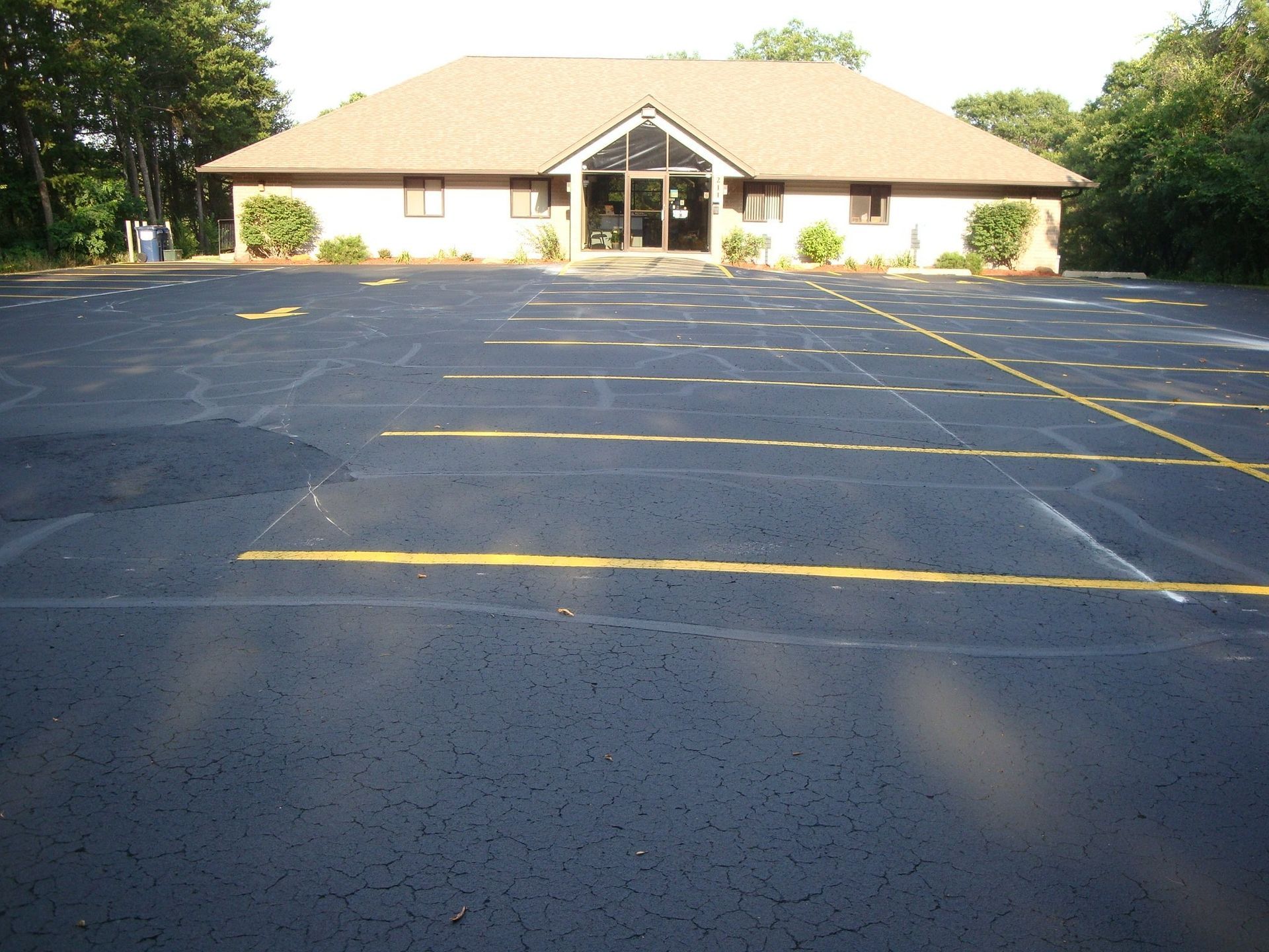 Exterior of a one-story building with a dark parking lot. The building has a brown roof and glass doors.