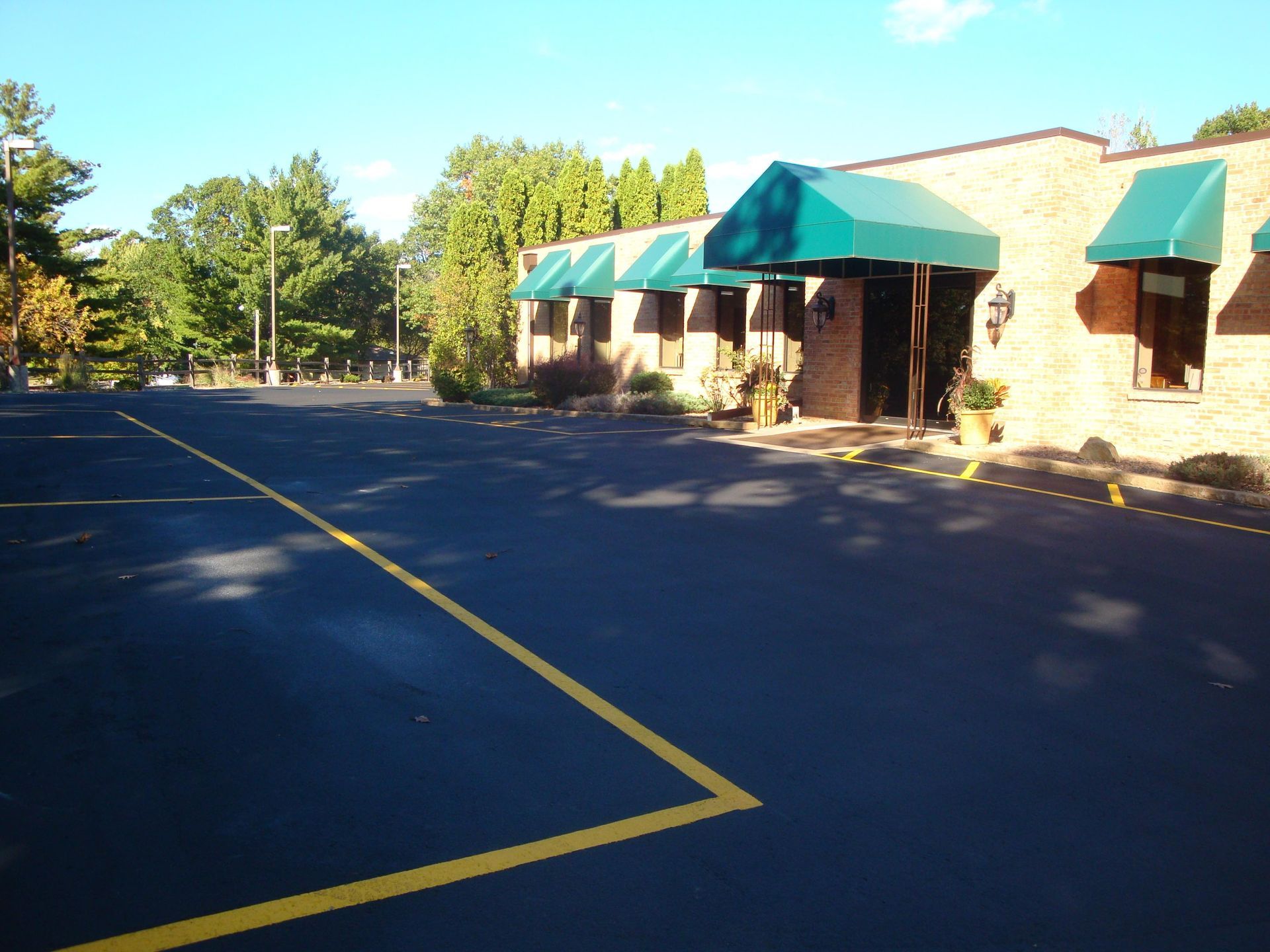 Building with green awnings, brick exterior, and empty parking lot with yellow lines.