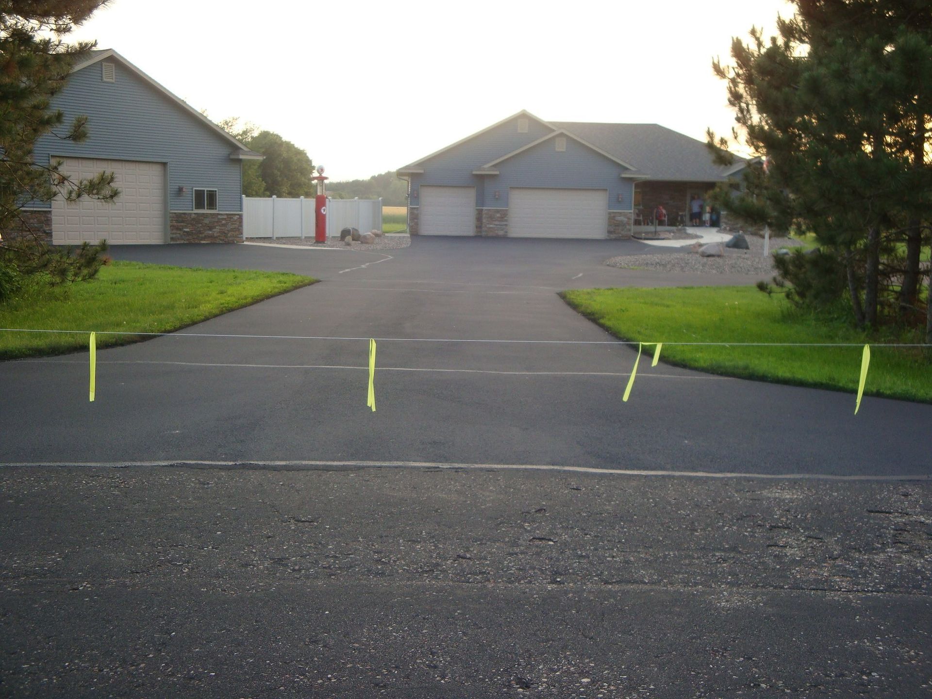 Driveway with yellow markers leading to houses with attached garages, set in a grassy area.