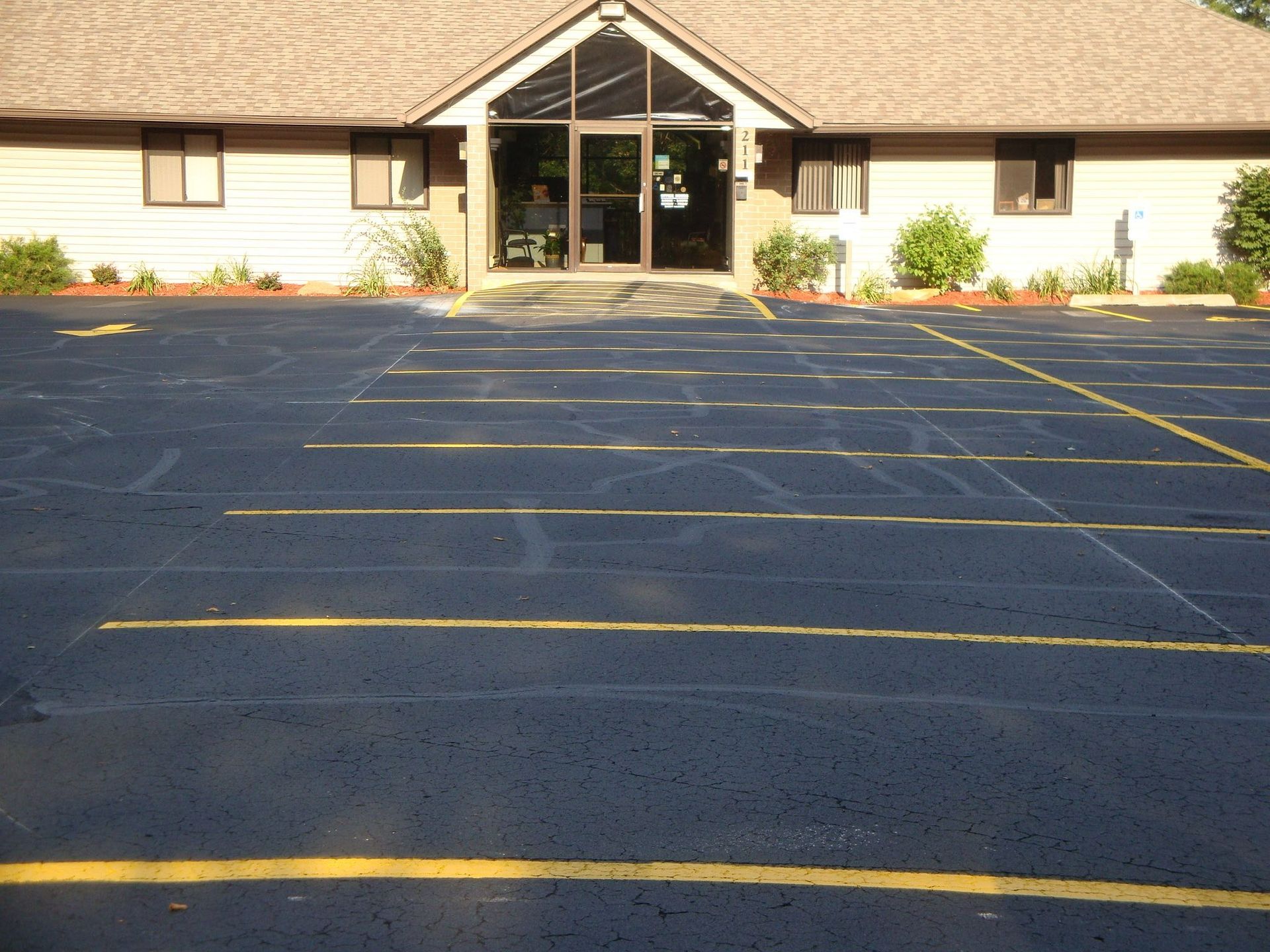 Asphalt parking lot with yellow lines in front of a one-story building.