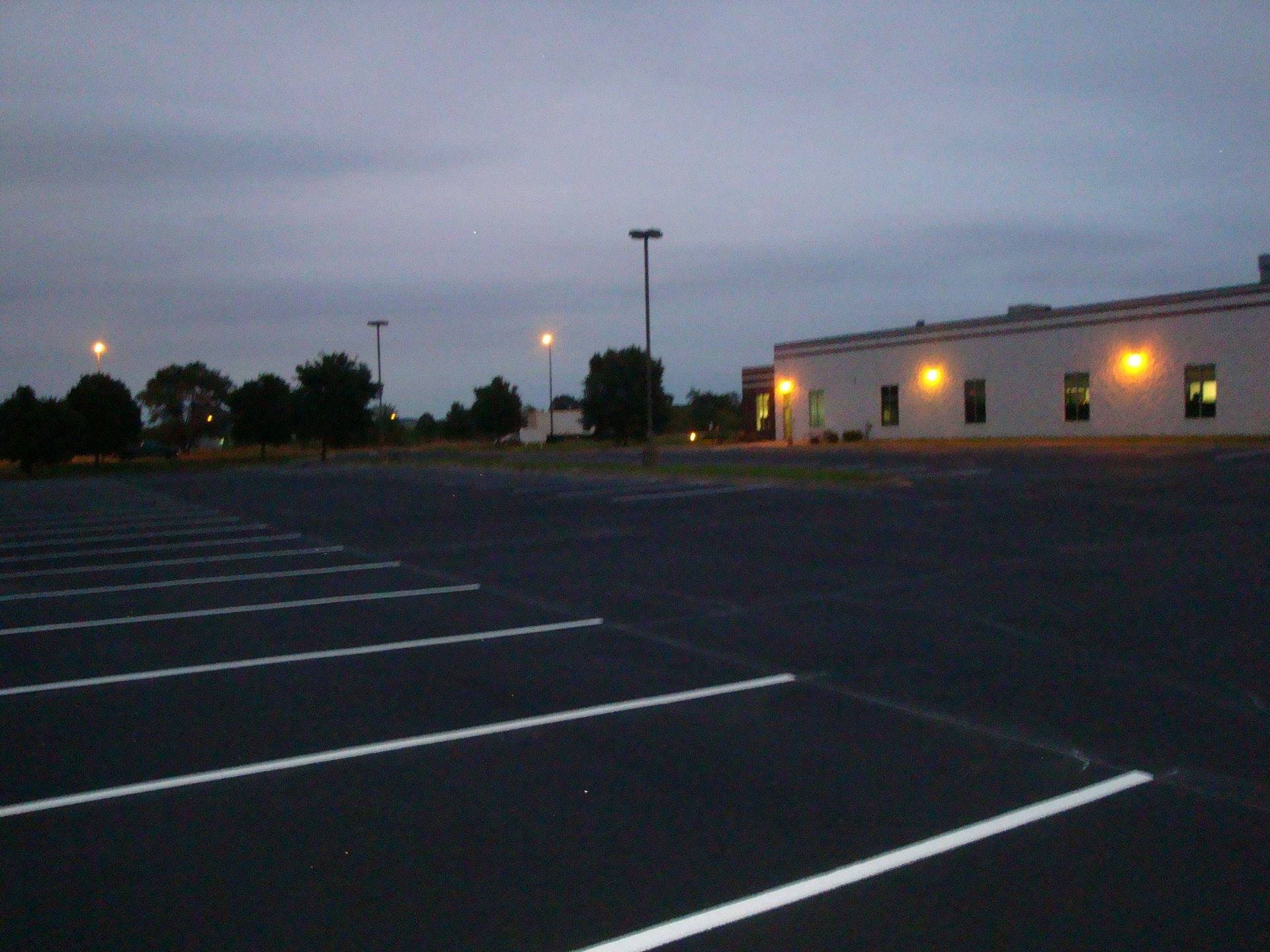 Empty parking lot in front of a building at dusk.
