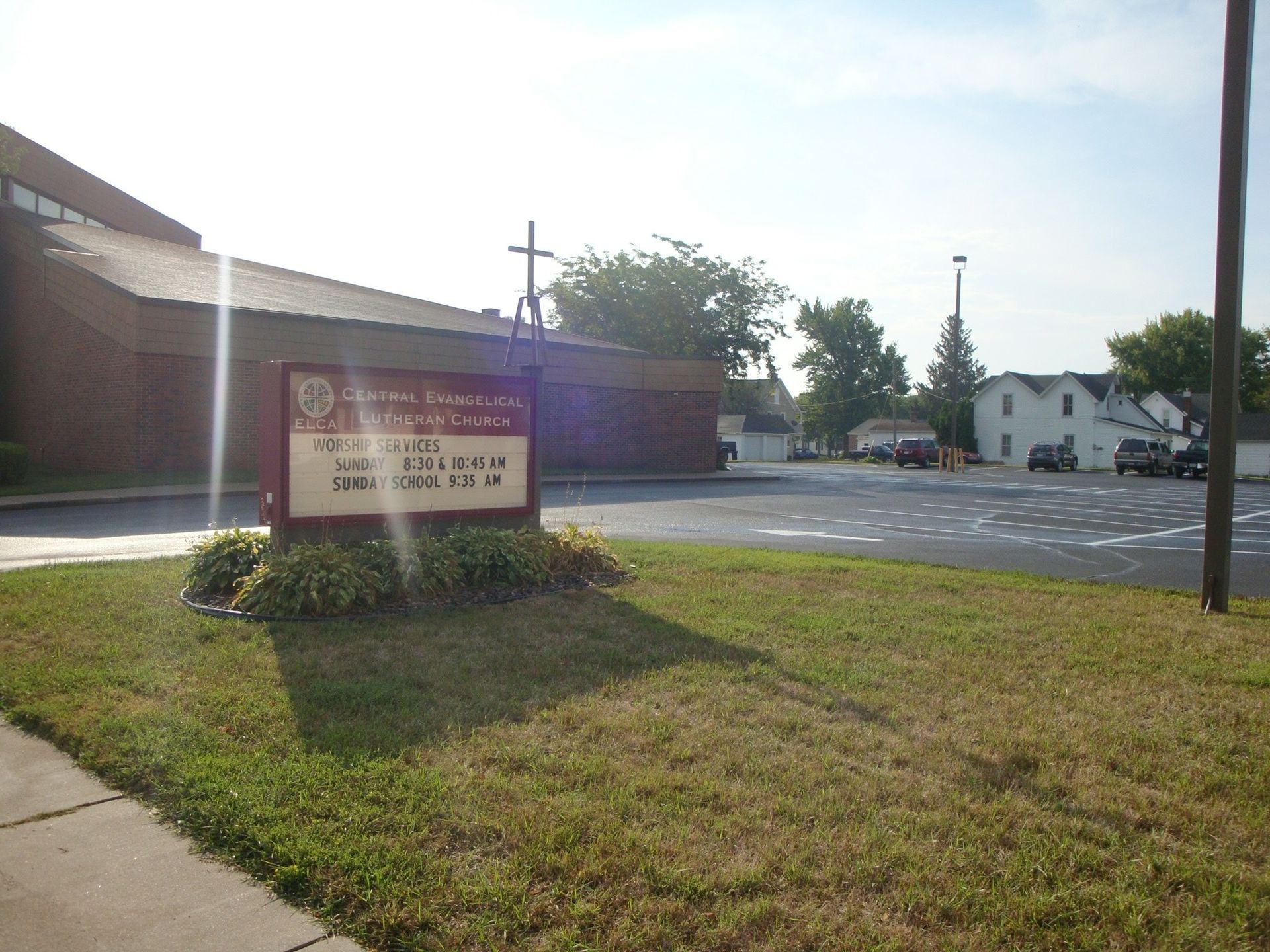 Church building with a sign, cross, and parking lot.