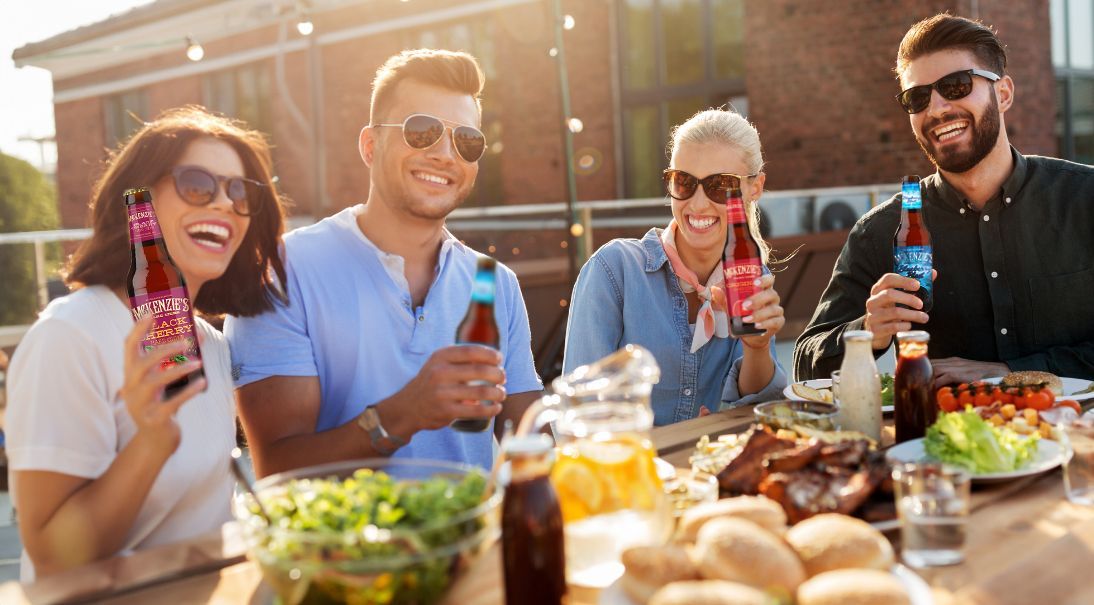 Friends enjoying McKenzies Hard Cider around a table with food