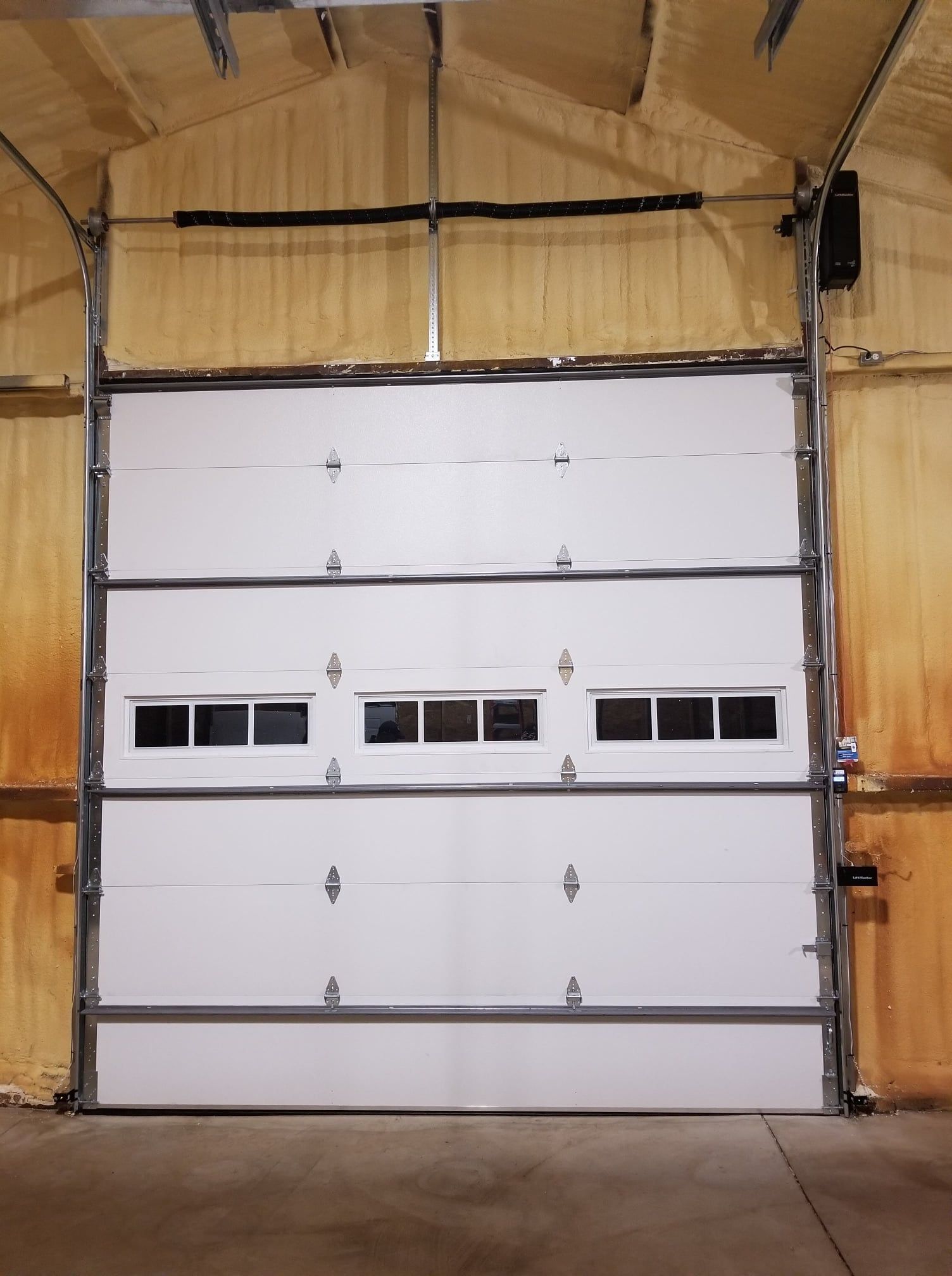 White garage door with windows, inside a tan warehouse.