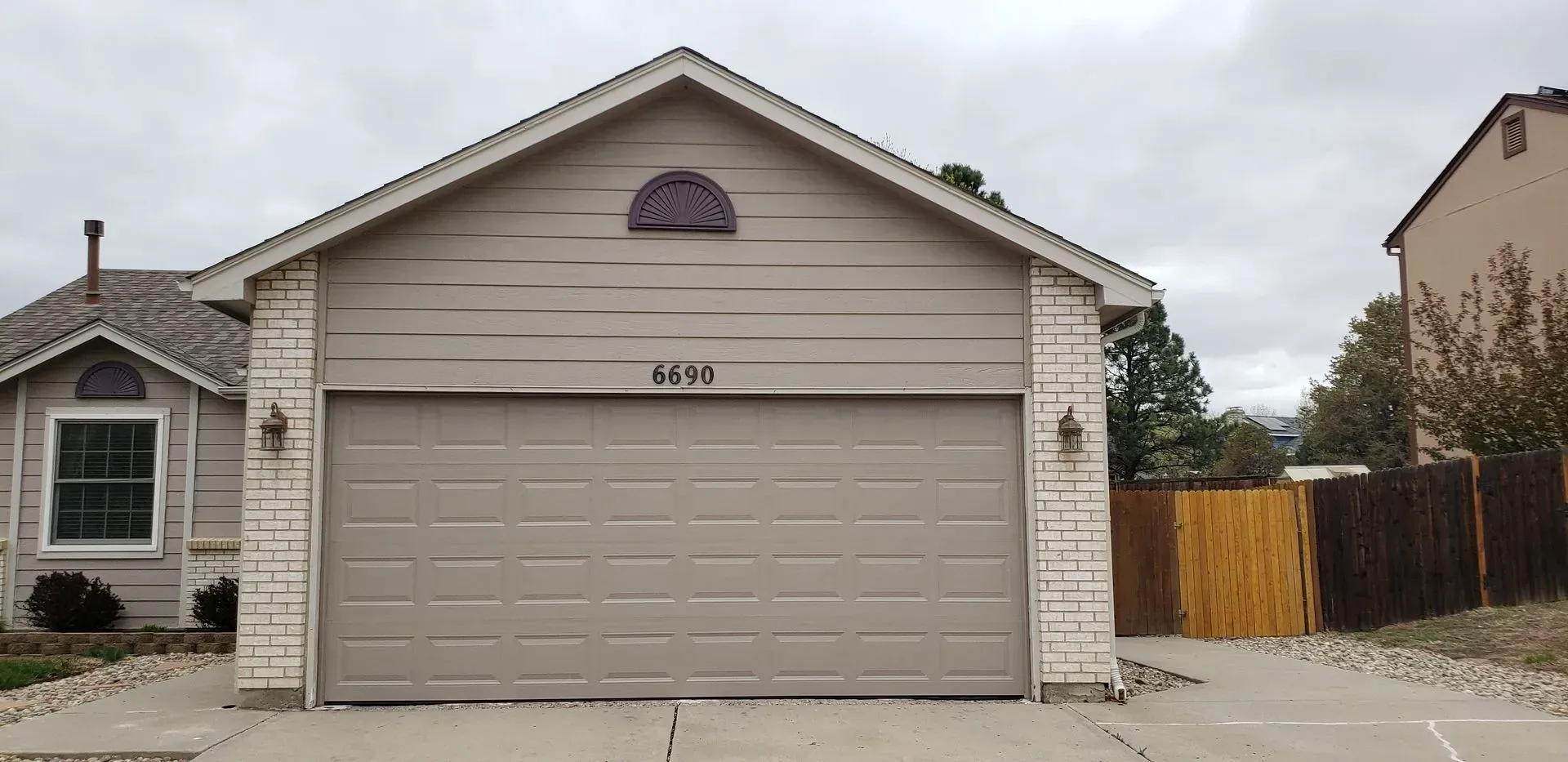 House with a garage, siding, and address 5890. Overcast sky.