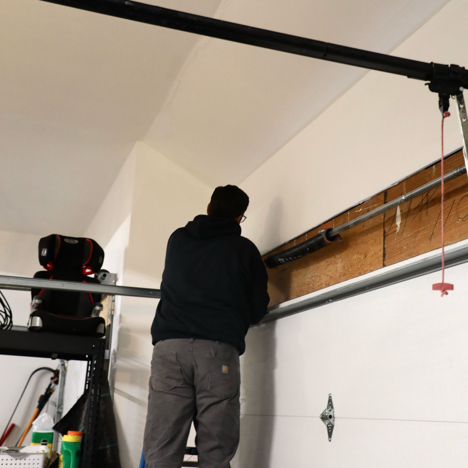 Person repairs garage door spring inside garage.