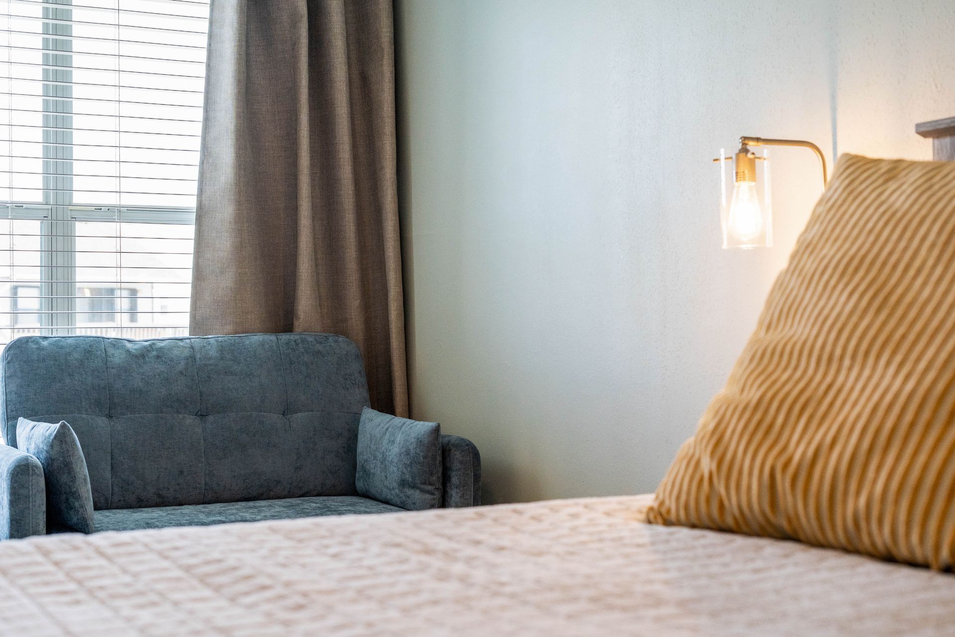 A bed with a couch and a window in a bedroom.