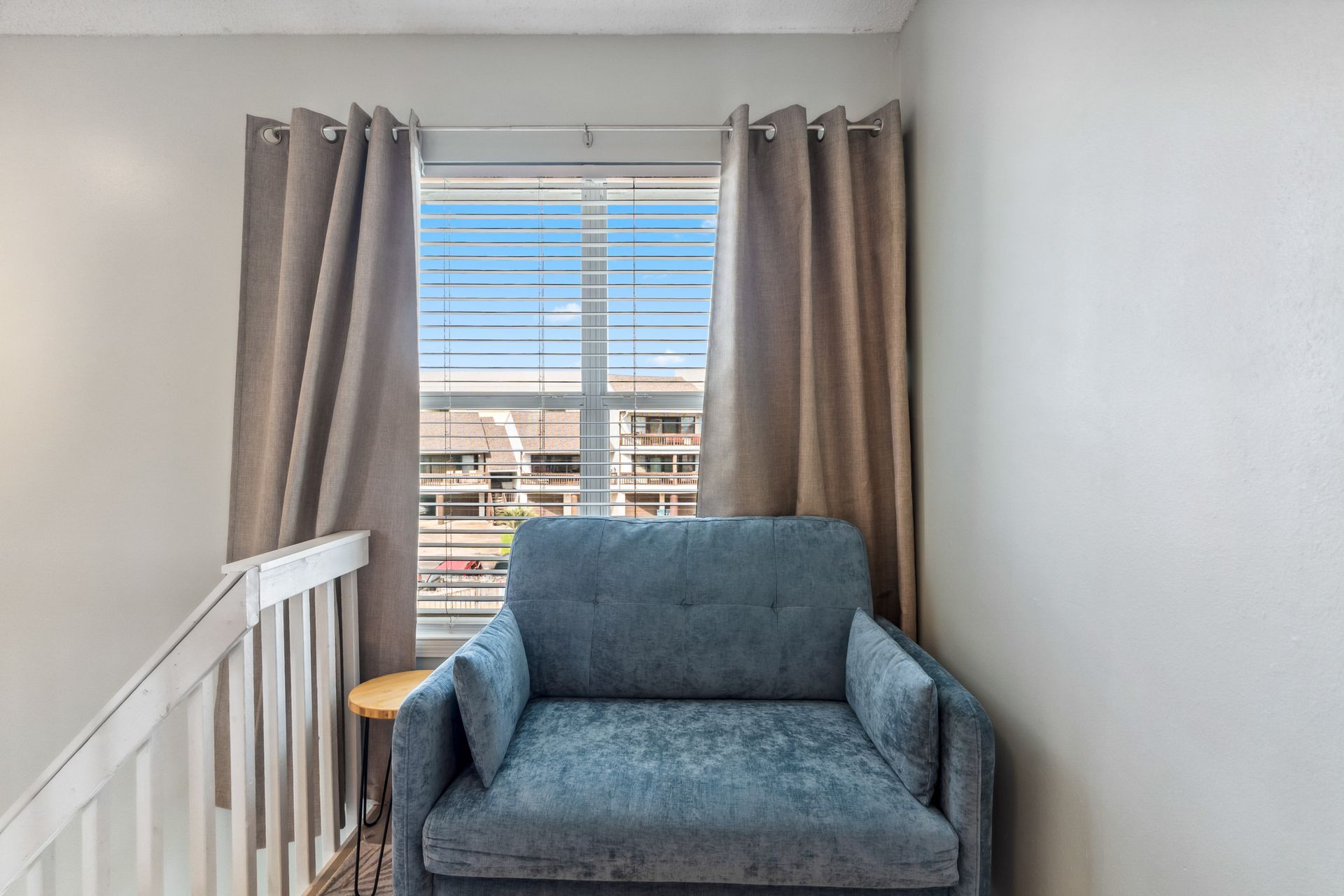A blue couch is sitting in front of a window in a living room.