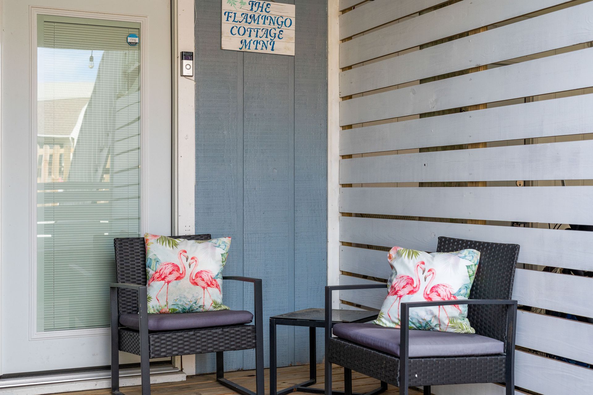 There are two chairs and a table on the porch.