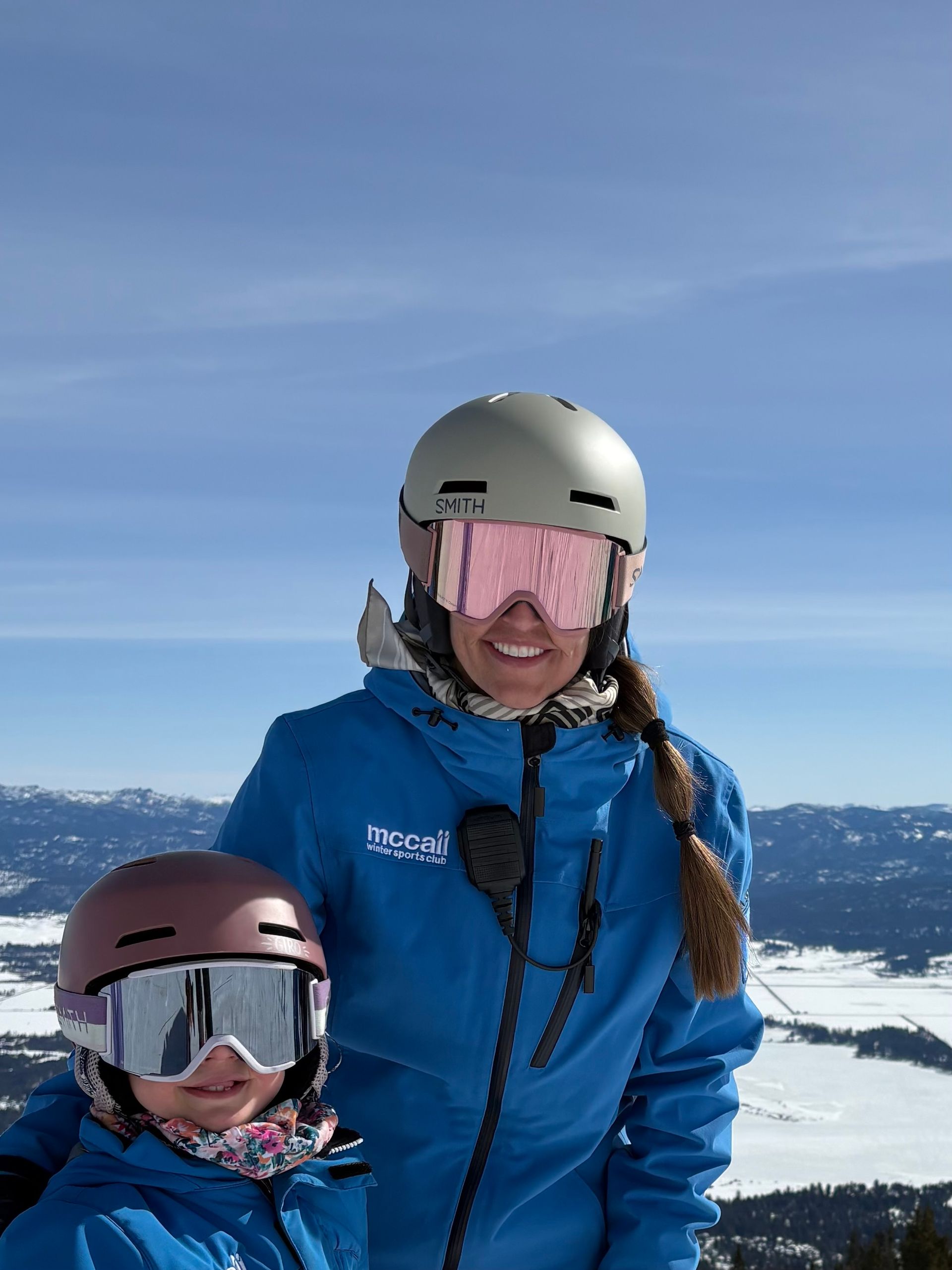 Four skiers in blue jackets posing on a snowy mountain slope under a clear sky