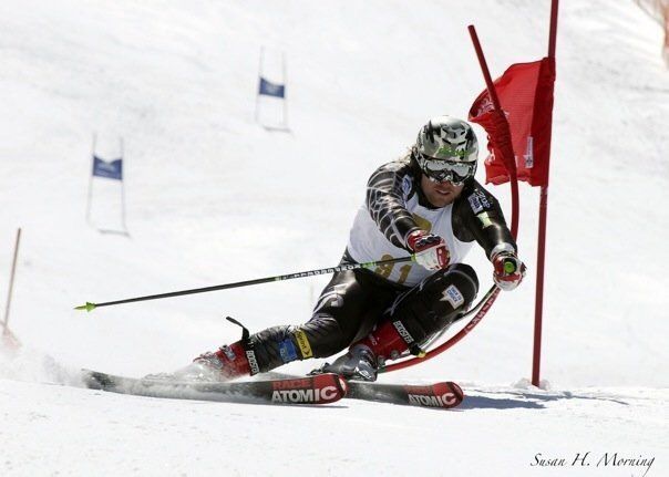 Skier in black and white racing through a slalom gate on a snowy course
