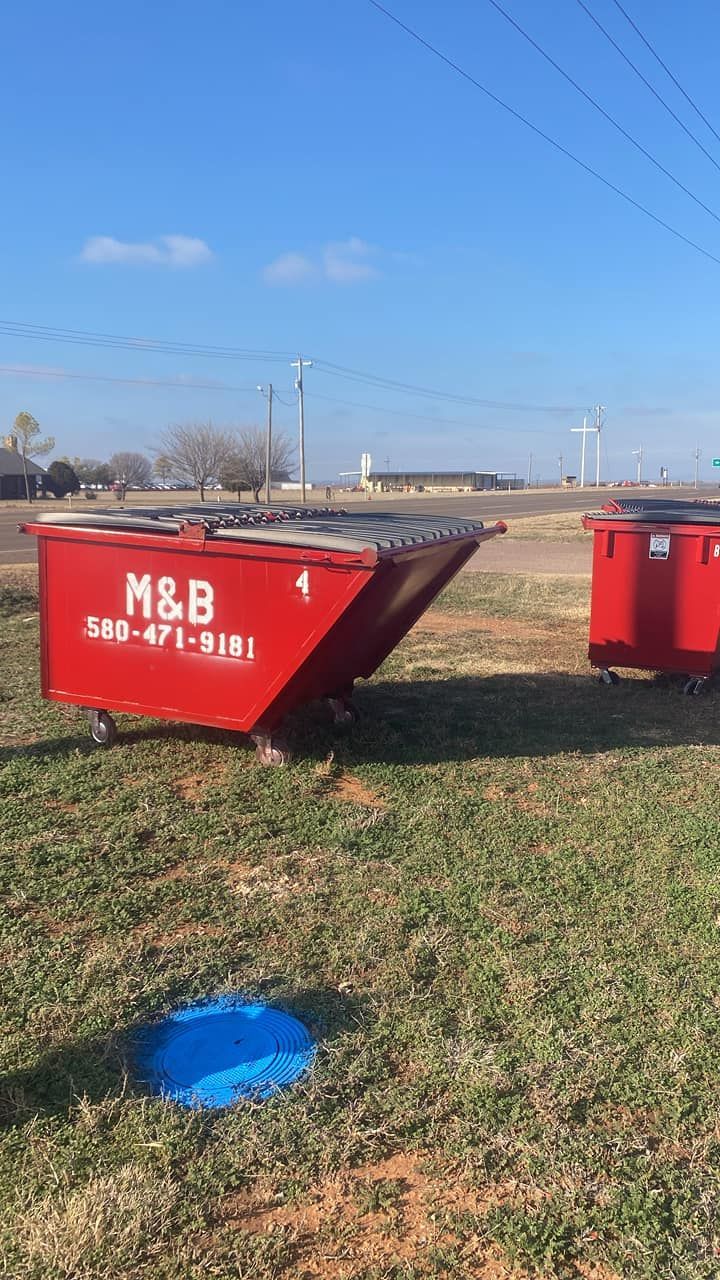 Two red dumpsters in a grassy field with power lines and a blue cover.