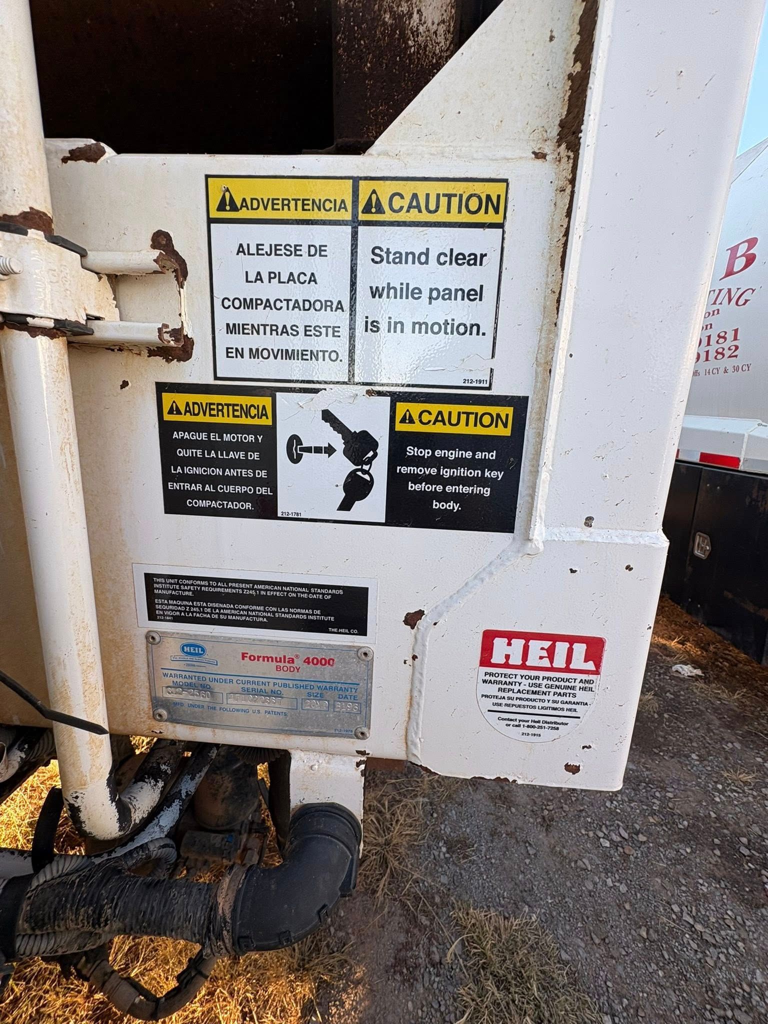 Signage on white truck, including cautions, warnings, and mechanical diagrams. 