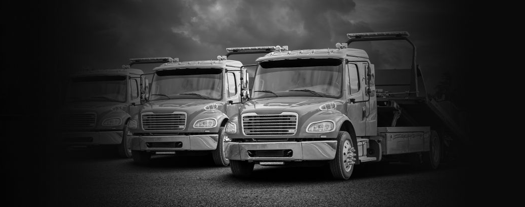 Two white semi trucks parked side by side on a dark road at night | Pasco Auto Diesel