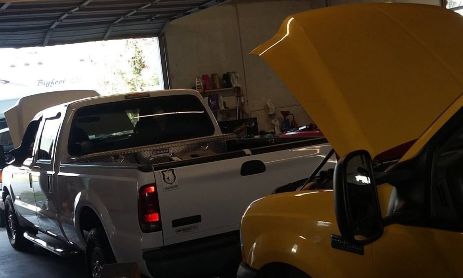 White truck and yellow truck, both hood up parked in garage in Port Richey, FL | Pasco Auto Diesel