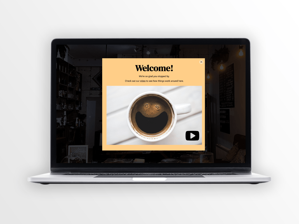 Laptop displaying a welcome screen with a coffee cup smiling on a white table.