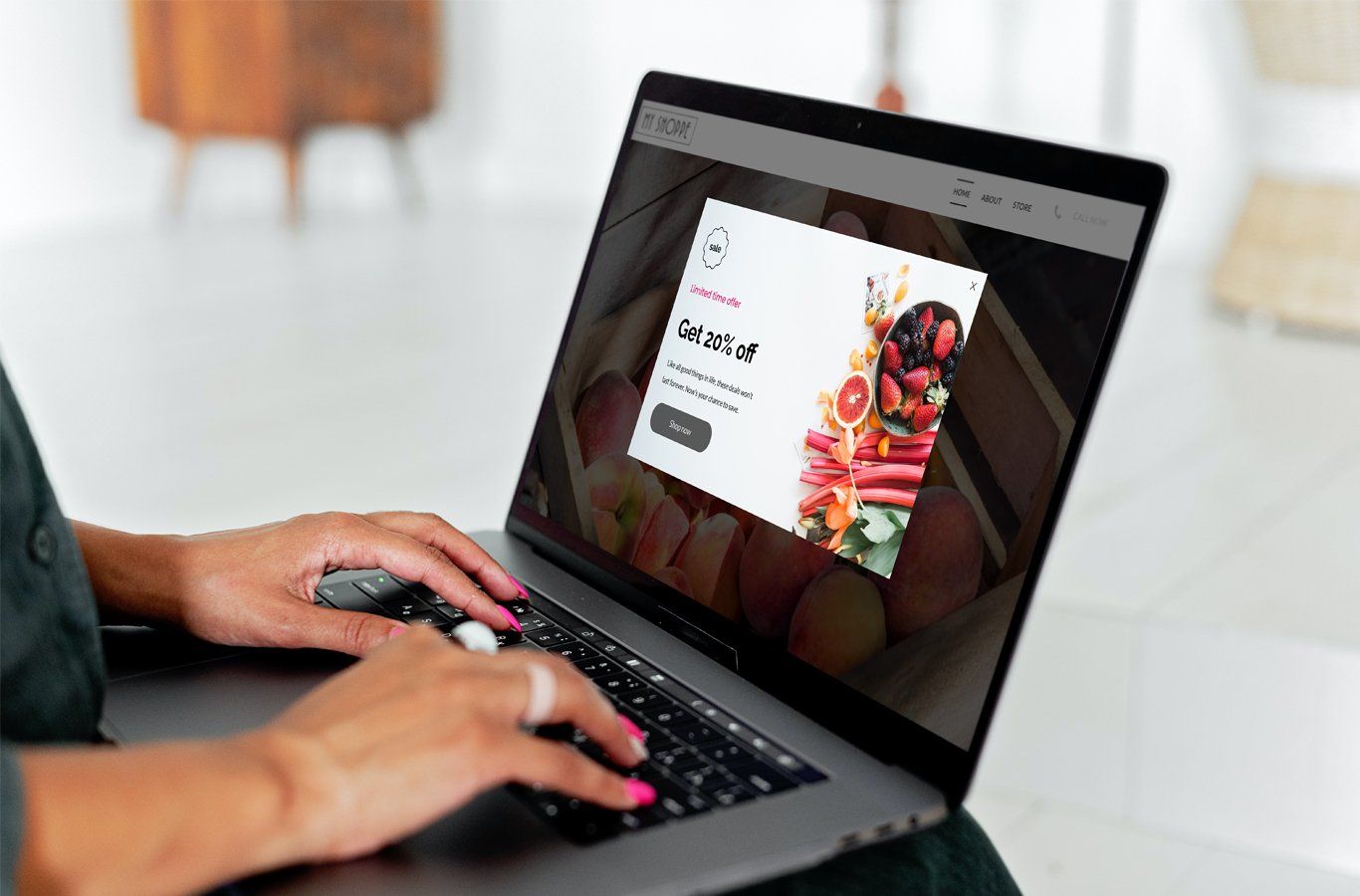 Person typing on a laptop, a website with a white popup ad displaying fresh fruit.
