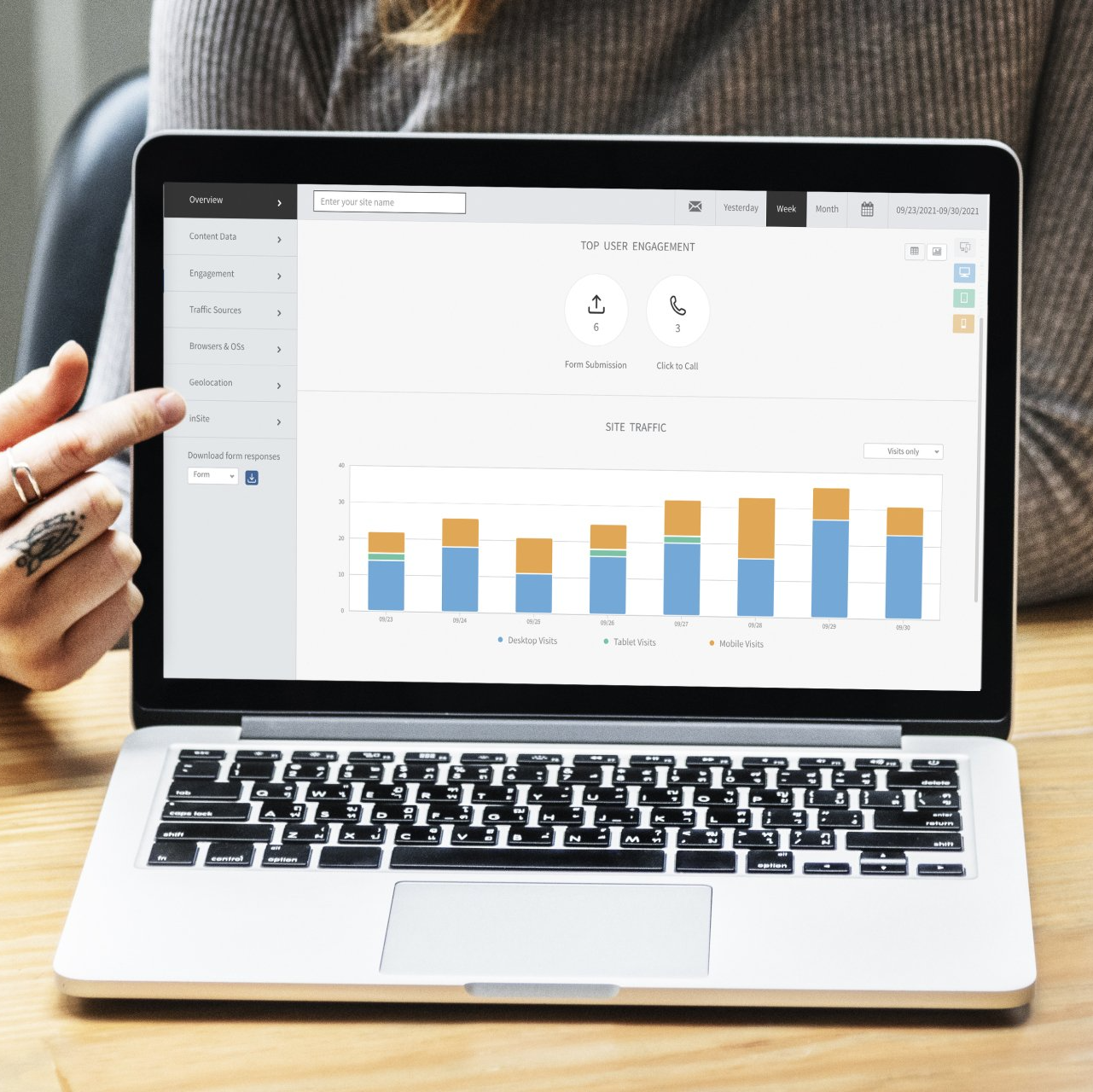 Person pointing at a laptop screen displaying a bar graph in blue and orange.