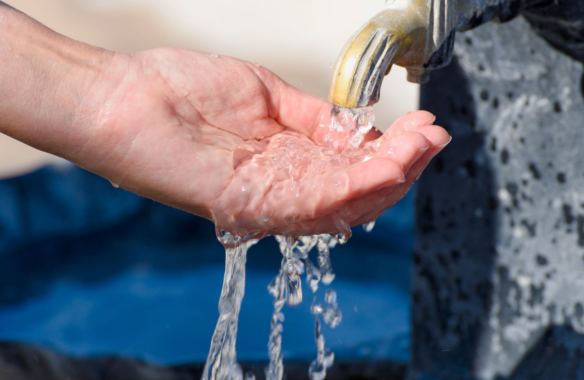A person is pouring water into their hand from a faucet.