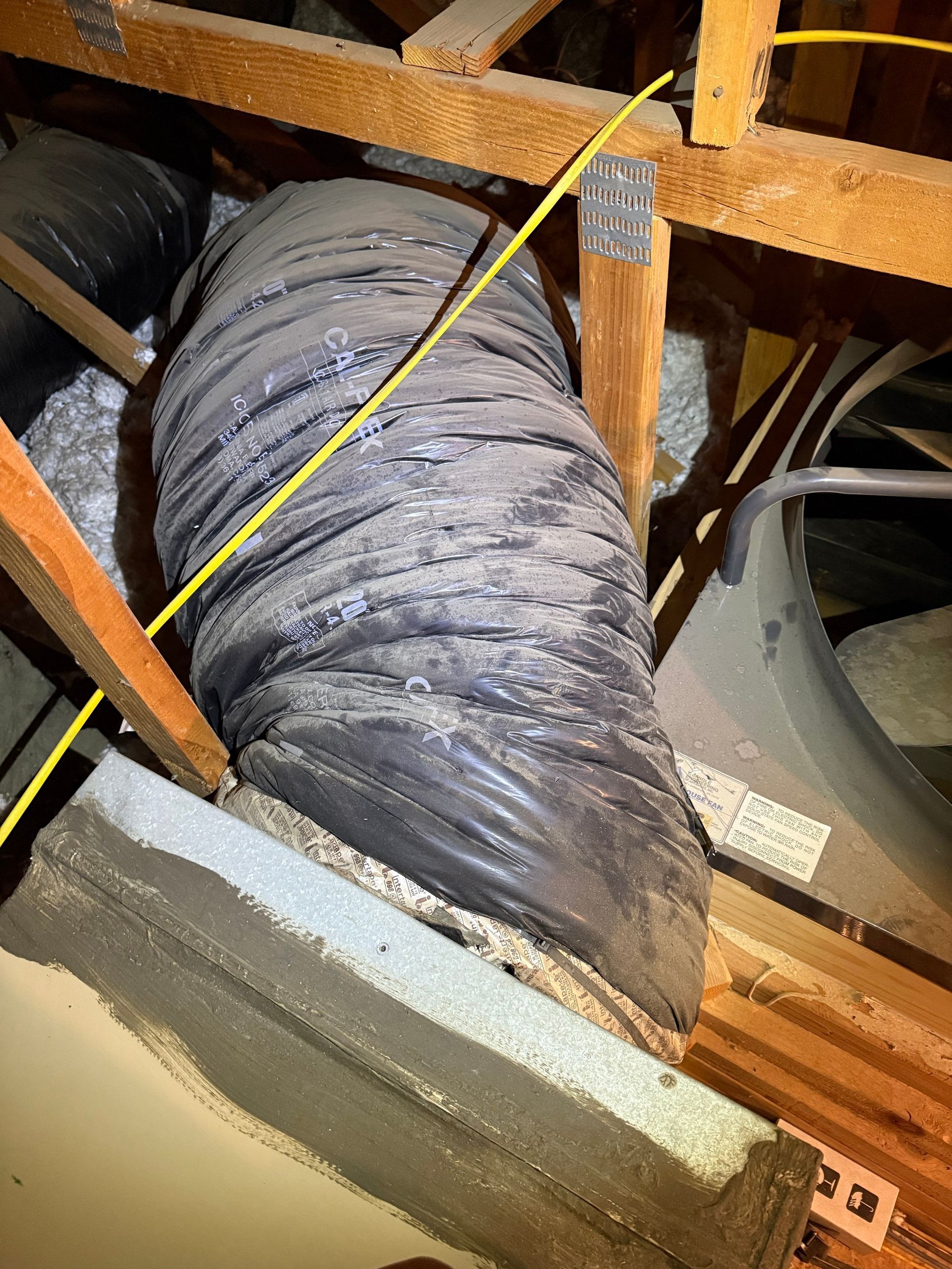 Damaged flex duct in the attic showing crushed and torn sections