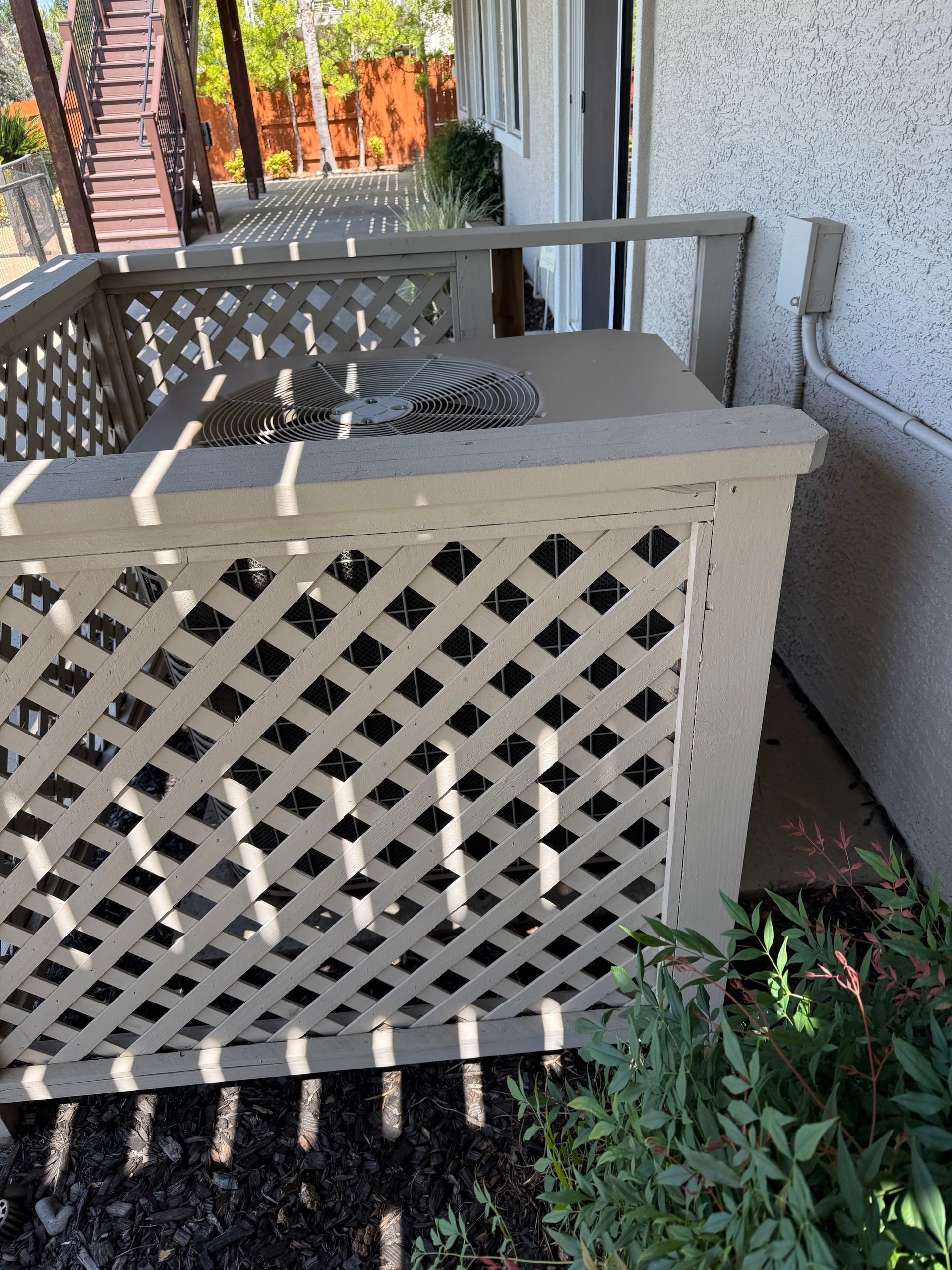 Outdoor unit behind a decorative lattice fence restricting airflow