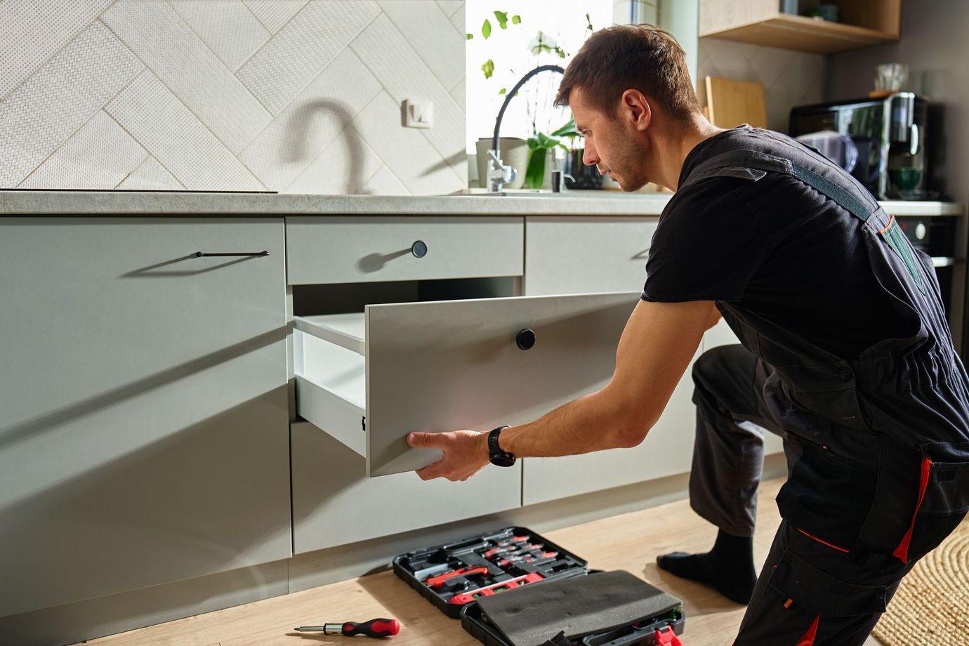 Technician installing a white kitchen drawer with tools on the floor
