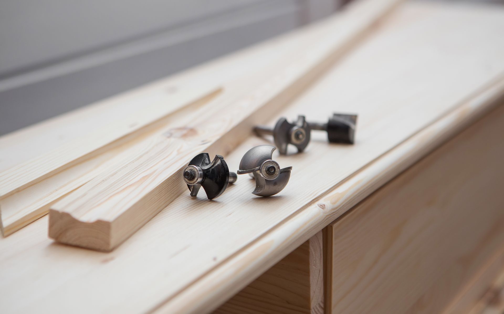 Wooden trim pieces and metal hardware parts laid out on a white workbench.