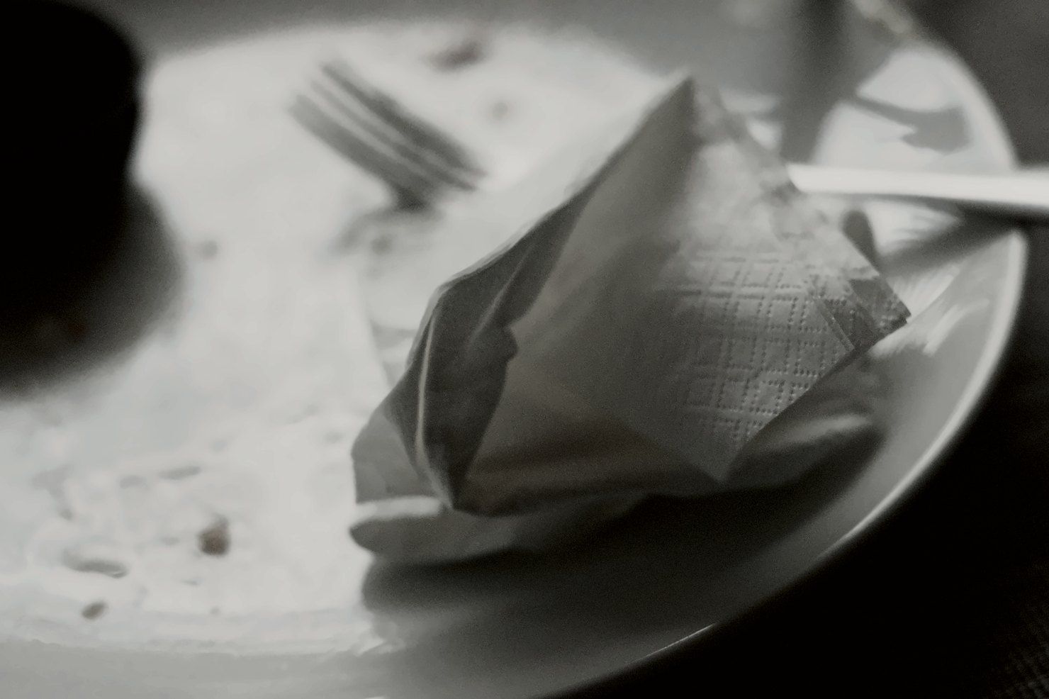 Used paper napkin and cutlery left on an empty plate after a meal