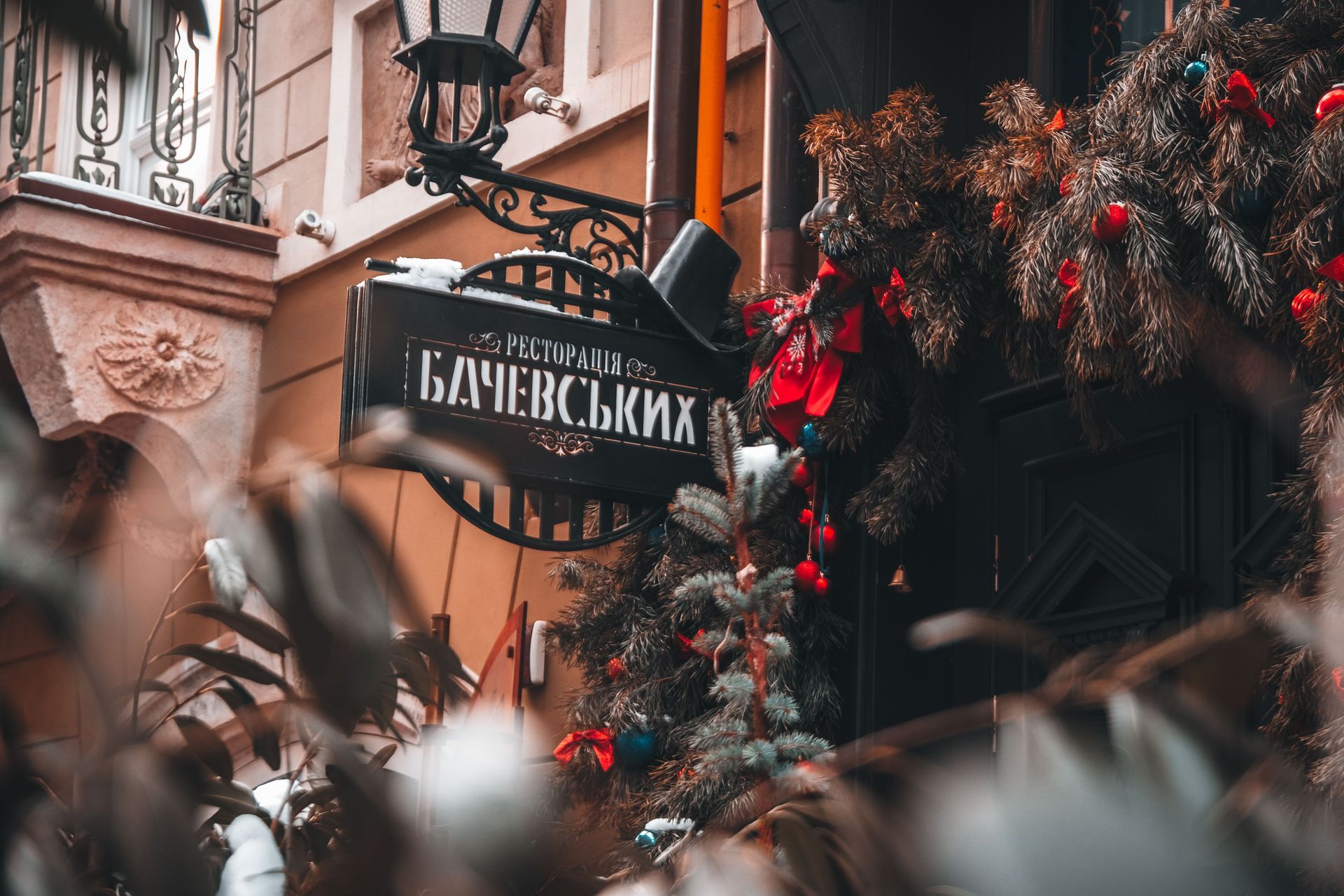 Festive street scene with a Cyrillic sign, red decorations, and blurred foliage in the foreground