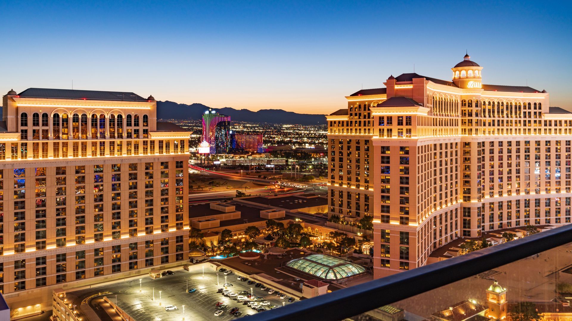 Night view of a brightly lit casino hotel resort complex with twin towers and city lights
