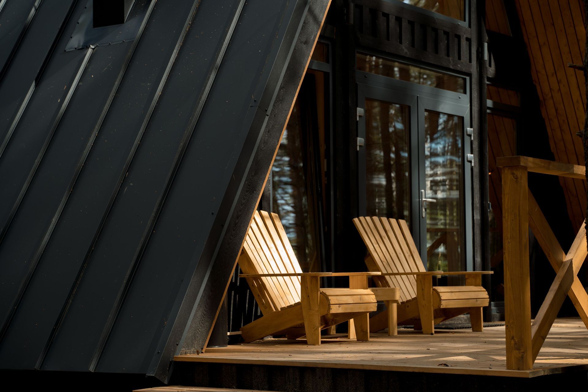Two wooden chairs side by side on a shaded porch in warm afternoon light.