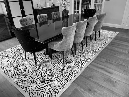 Dining room with a black table and velvet chairs on a zebra-print rug.