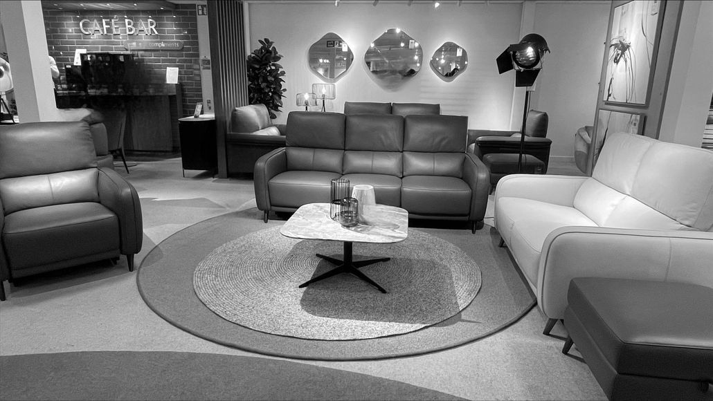 Living room with gray sofas, rug, and decorative mirrors on the wall.