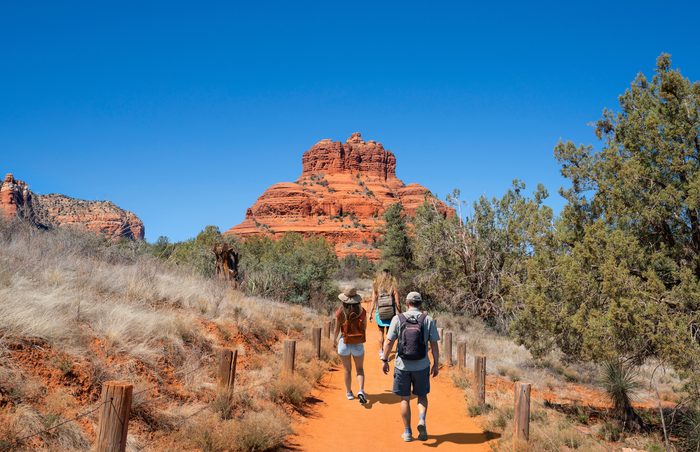 A group of people are walking down a dirt path in the desert.