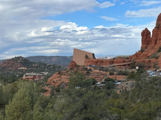 A large building is sitting on top of a hill surrounded by trees.