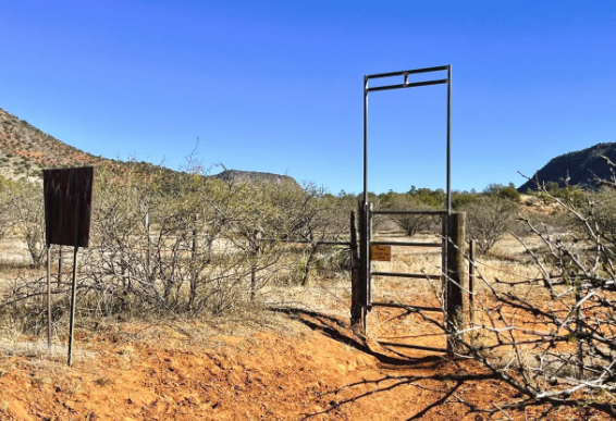 A gate in the middle of a desert with mountains in the background