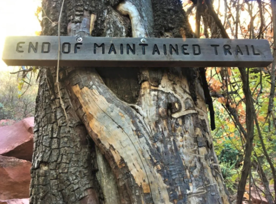 A sign on a tree that says end of maintained trail